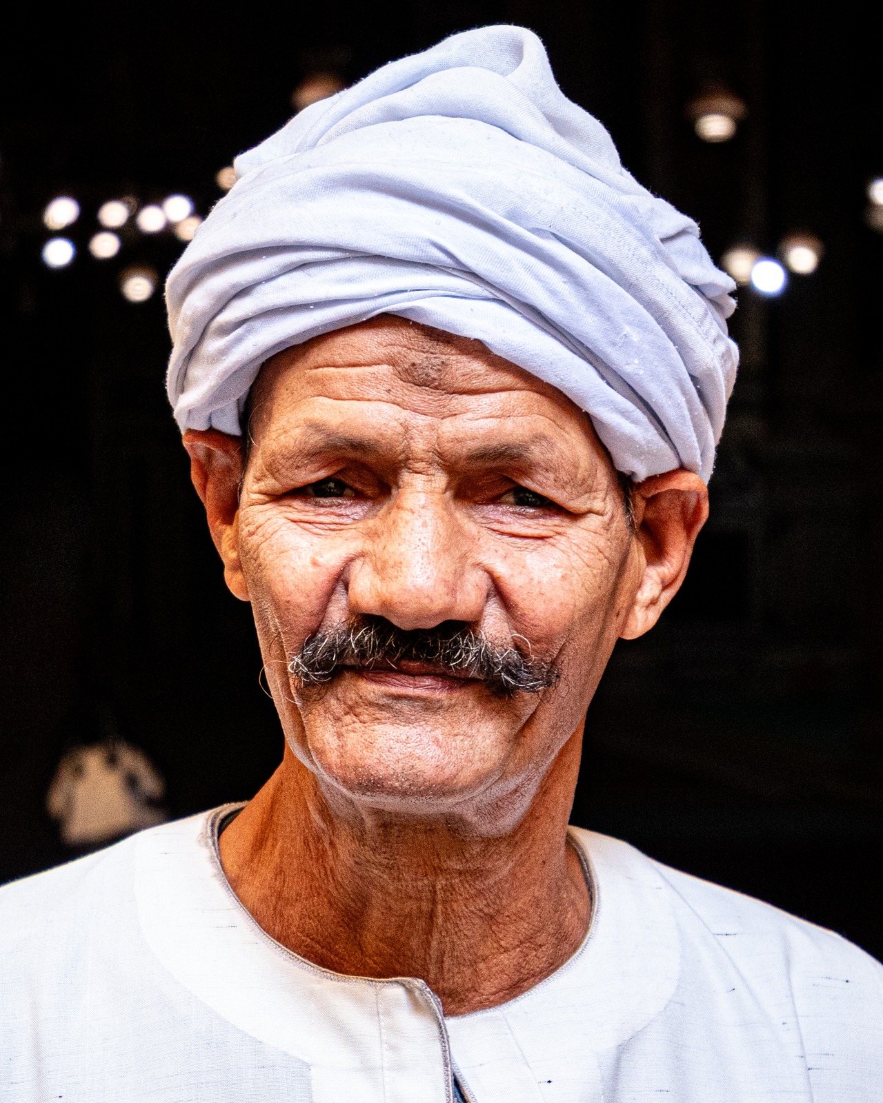 Close portrait of an older man with a moustache wearing a white turban